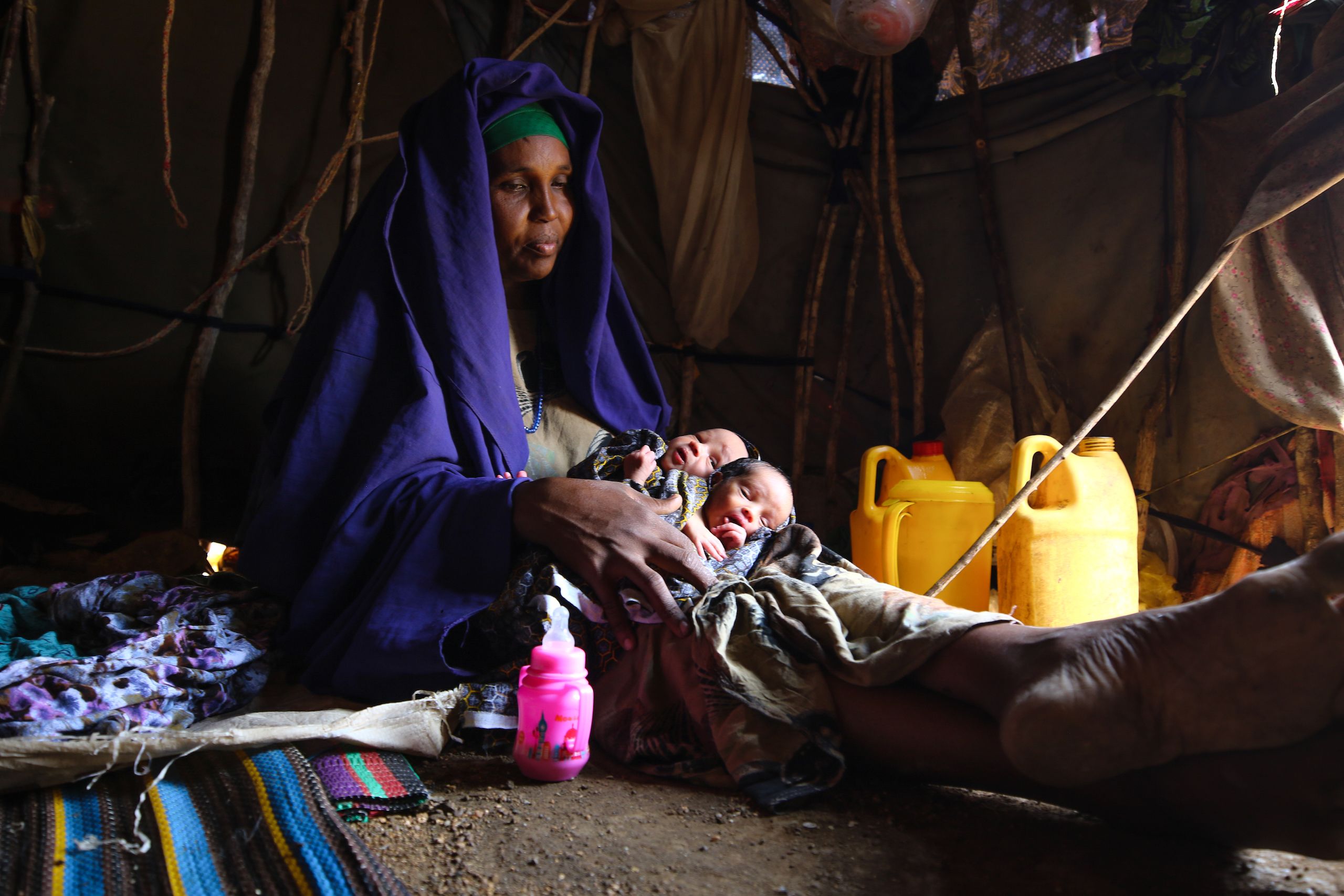 A woman holds two babies.