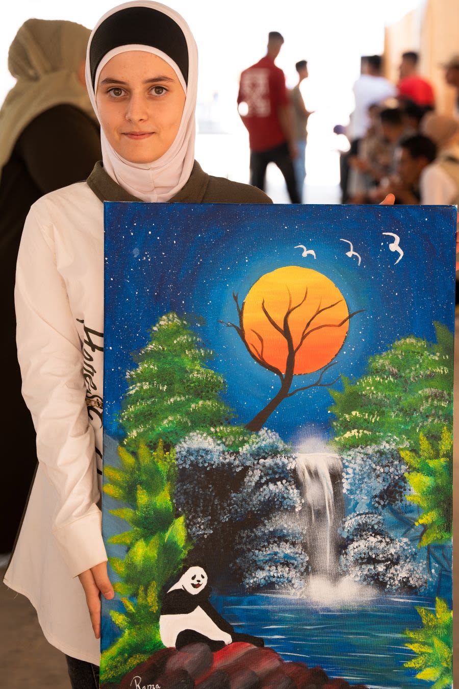 A girl holds a painting of nature.