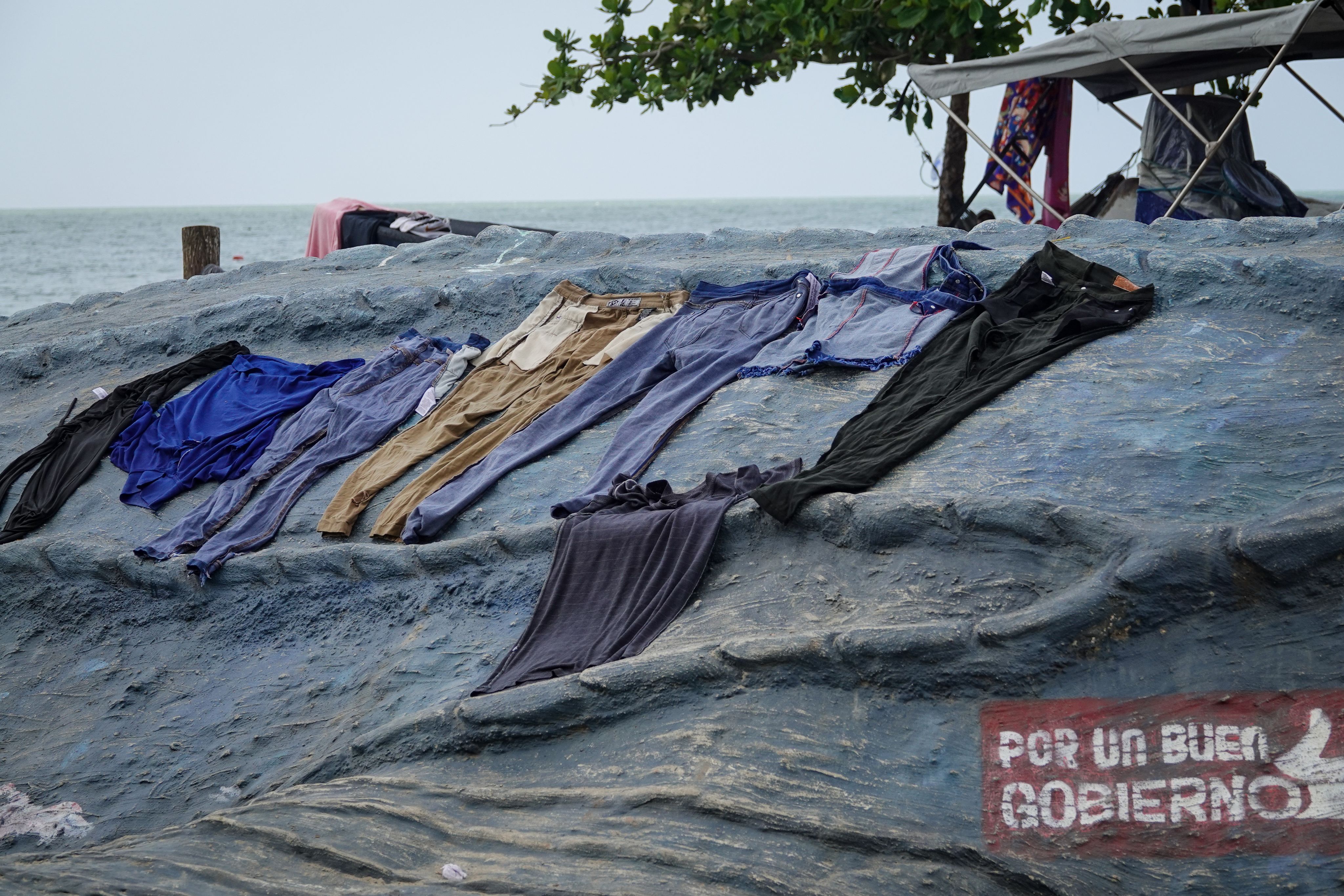Various trousers placed on a rock formation to dry after being washed.